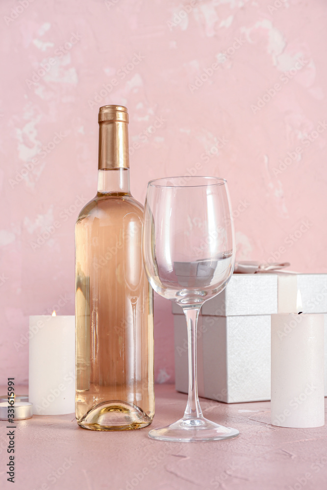 Bottle of wine, glass, candles and gift on table