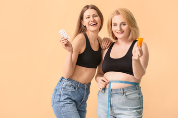 Wall Mural - Women with weight loss pills on color background