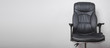 Black leather office chair in grey background.