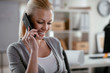 © JustLife - Businesswoman using phone. Happy young woman talking on smartphone in office.