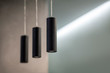 Part of modern loft interior with clean design, ascetic minimal background and three lamps in black tubes, hanging from the ceiling. Concrete walls, gray natural colors, indoors, soft selective focus.