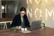 © pokryvka - Business woman in a black suit and glasses sitting at a table in a cafe working at a laptop holding a notebook with records