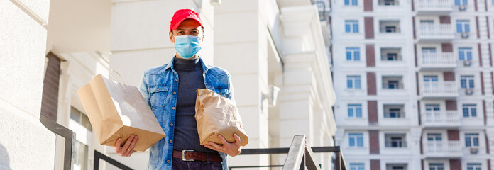 Delivery man holding paper bag with food on white entrance of house background , food delivery man in protective mask