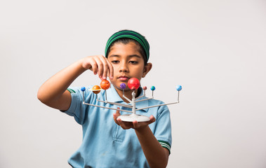 indian schoolgirl / girl child studying planets or planetary science with 3d model of our solar syst