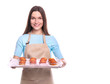 © LumenSt - Young woman in an apron with  tray of muffins isolated on white background.