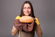 © LumenSt - Young woman in an apron with fresh bread on gray background.