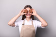 © LumenSt - .Young woman in an apron with fresh bread on a gray background. Cook concept