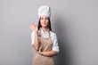 © LumenSt - .Young woman in an apron with fresh bread on a gray background. Cook concept