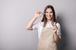 © LumenSt - Young woman in apron on grey background. Hairdresser concept
