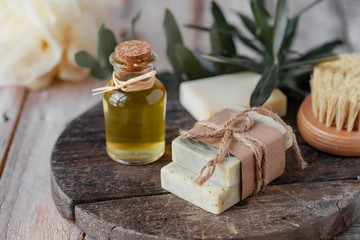 Concept of natural ingredients in cosmetology for gentle skin care. Organic olive oil in glass bottle, handmade soap bars. Atmosphere of serenity and relax. Rustic wooden background, close up.