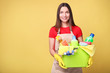 © LumenSt - Young woman in apron  on  yellow background. Cleaning concept