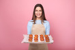 © LumenSt - Young woman in apron with cupcakes on a yellow background