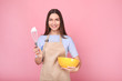 © LumenSt - Young woman in apron is standing by yellow background
