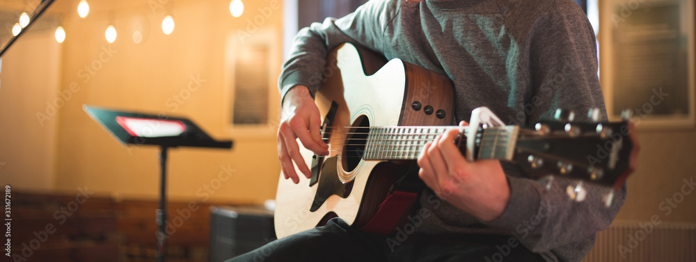 Young man playing on acoustic guitar - obrazy, fototapety, plakaty 