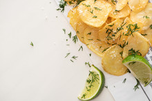 Top View Of Crunchy Potato Chips With Salt Near Sliced Lime On White
