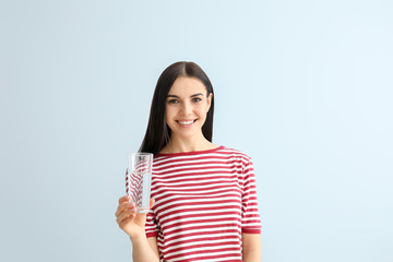 Sticker - Beautiful young woman drinking water on color background