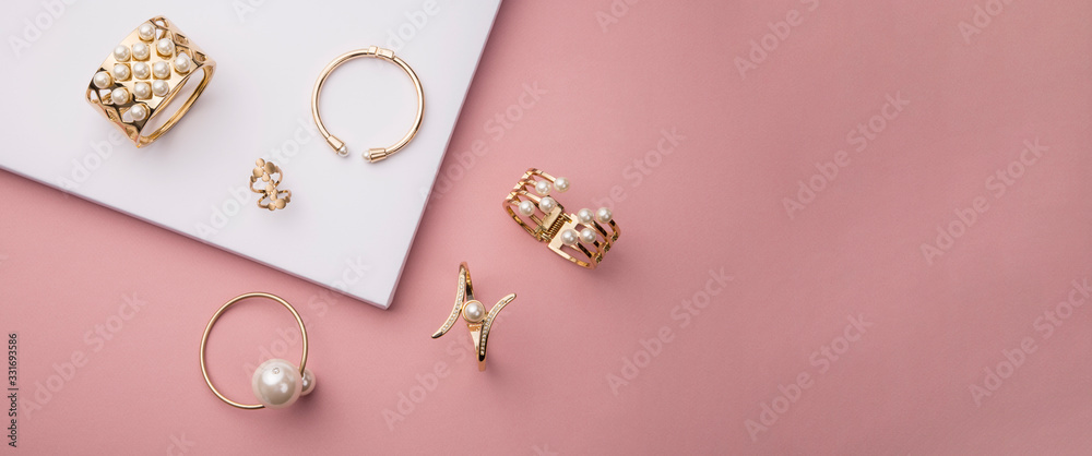 Top view of golden with pearl bracelets on pink and white background with copy space - obrazy, fototapety, plakaty 
