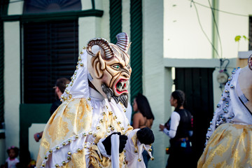 Wall Mural - closeup man in scary devil costume passes by city street at dominican carnival