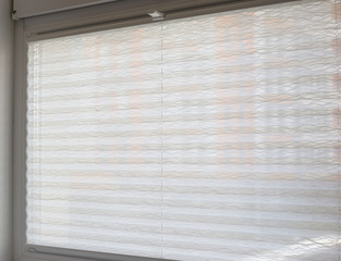 Aufkleber - Pleated blinds close up on the window in the interior. Home blinds - cordless pleated modern shades on apartment windows. White color fabric. Bottom up top down pleated curtains.