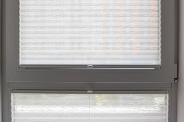 Aufkleber - Pleated blinds close up on the window in the interior. Home blinds - cordless pleated modern shades on apartment windows. White color fabric. Bottom up top down pleated curtains.