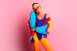 Back in time 90s 80s. Stylish girl in retro colourful  vintage coat, orange leggings, and purple body, fashion trends, entertainment. 80's Fashion woman over pink background. Beautiful athletic girl.