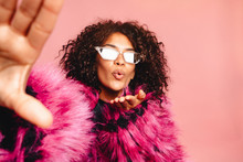 Indoor Self Portrait Of Young Pretty African Hipster Girl Wearing Pink Faux Fur Trendy Coat And Stylish Sunglasses ,smiling, Laughing, Making Selfie Joy,positive Emotions. Gesture, V Sign.
