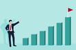 © Nikhom - Business man pointing finger to flag on top of highest bar graph.