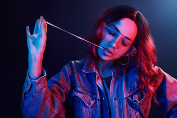 Wall Mural - Portrait of young girl in glasses with bubble gum in red and blue neon in studio