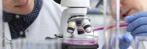 Fotografía Close-up view of biochemist adding bright violet substance in glass container