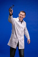 Male doctor in a white coat posing on a blue background