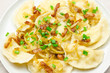 Homemade dumplings with toasted onions and bacon. Traditionally, the Ukrainian dish is decorated with green onions. Plate with dumplings on the table