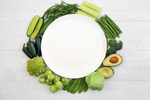 Vegan Health Food Wreath With Green Vegetables To Boost The Immune System Surrounding A White Empty Plate On Rustic Wood. Foods High In Vitamins, Minerals, Antioxidants & Dietary Fibre. Ethical Eating