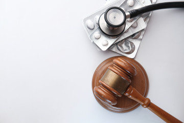 top view of Judge gavel and stethoscope with pills on table 