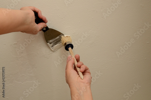 Cuadros en Lienzo Woman plasterer repairing the wall with putty