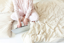 Mobile Office At Home. Young Woman In Pajamas Sitting On Bed At Home Working Using On Laptop Pc Computer. Lifestyle Girl Studying Indoors. Freelance Business Quarantine Concept.
