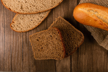 Slices of brown and white bread on kitchen board with baguette