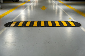 Striped black and yellow speed bump on a road.