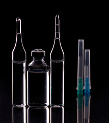 Wall Mural - Glass ampoules close up. Medical ampoules. Medical ampoules, syringe needles on a black background.