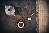 Cup of coffee, coffee pot and beans on a dark background. Top view with copy space for text.