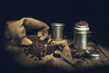 Coffee beans in ancient coffee pot on wooden table.