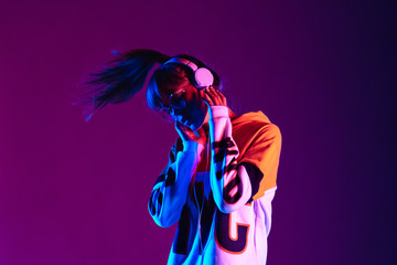 stylish fashion teenager model wearing hoodie and headphones listening dj music dancing in purple ne