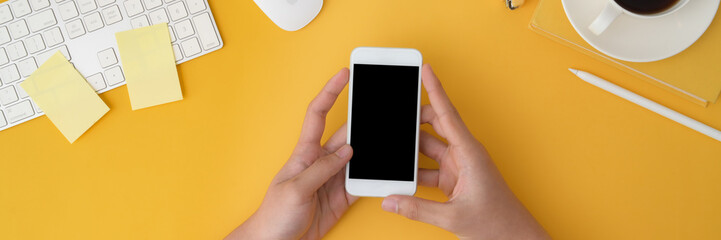 Cropped shot of a man holding smartphone on yellow background