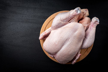 Wall Mural - Raw chicken on wooden board on black background.