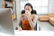 © torwaiphoto - Asian woman sneezes. She uses a tissue to cover her mouth and she is working at home.