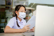 © anuchit2012 - social distancing concept, Junior Primary school girl Do homework at home with laptop. the school is closed during an outbreak of the Coronavirus Covid-19 and Dust PM2.5 in Bangkok Thailand asia