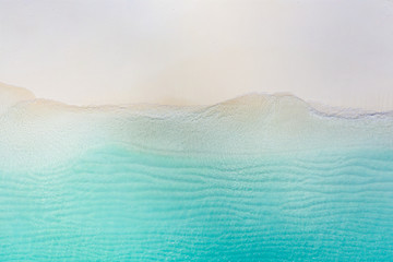 Summer seascape beautiful waves, blue sea water in sunny day. Top view from drone. Sea aerial view, amazing tropical nature background. Beautiful bright sea with waves splashing and beach sand concept