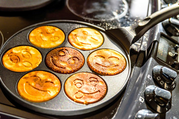 pancake frying pan with smile face pancake cooking on cooker in kitchen