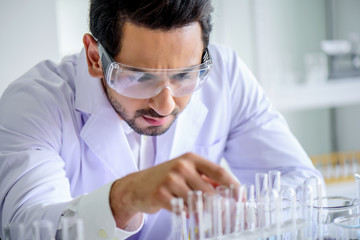 Wall Mural - attractive happiness scientist man lab technician assistant analyzing sample in test tube at laborat
