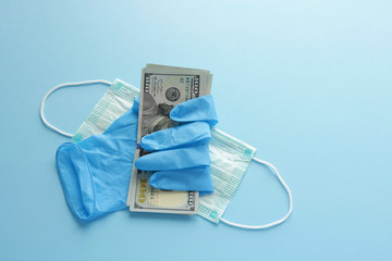 rubber glove holds dollar banknotes protective medical mask on blue background