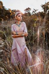 Wall Mural - beautiful young fashionable woman in dress on the field at sunset